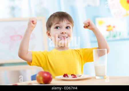 Garçon enfant de manger des aliments sains et montrant sa force Banque D'Images