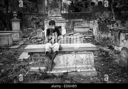 Calcutta, le Bengale occidental, en Inde. Apr 15, 2011. Dans un cimetière désaffecté de Calcutta un enfant inhale de la colle tout en restant assis sur une tombe. (Mars 2011) -- Kolkata (Calcutta) est un tournant dans le sous-continent indien. Ville d'un glorieux passé colonial (ancienne capitale de l'Inde britannique jusqu'au début du xxe siècle) voit maintenant comment d'autres villes du pays, comme Bombay ou New Delhi, la croissance de l'économie du pays. Entre-temps, le bengali ville reste liée à la stigmatisation de la pauvreté et du sous-développement depuis le déclin de l'économie dans les années après l'indépendance de l'Inde. C'est également envisager Banque D'Images