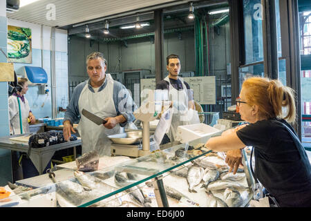 Femme aux cheveux rouges client regarde poissonnier prépare son ordre de marché aux poissons Darne de thon au marché central de Florence Banque D'Images