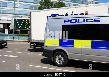 Une partie de l'arrière d'un fourgon de police et d'autres véhicules circulant autour d'un rond-point à Tolworth, Surrey, Angleterre. Banque D'Images