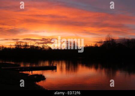 Solstice d'hiver coucher du soleil reflétée dans l'eau à Lakeside Country Park, Eastleigh, Hampshire, England, UK Banque D'Images