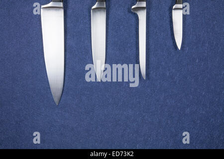 Quatre gros couteau de cuisine lame en argent brillant sur fond bleu Banque D'Images