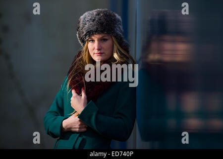 Un jeune cool 'scandinavian' femme blonde adolescente portant un manteau vert et chapeau de fourrure à l'extérieur seul , Royaume-Uni Banque D'Images