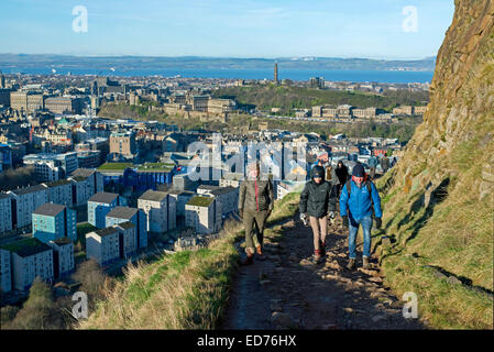 Les promeneurs sur la route radicale sous Salisbury Crags avec la ville d'Édimbourg, dans l'arrière-plan sur un jour d'hiver ensoleillé. Banque D'Images