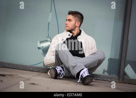 Beau jeune homme assis contre la fenêtre boutique abandonnés Banque D'Images