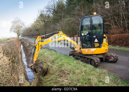 Le nettoyage des fossés de drainage en bordure de route qui avait été envahi par l'utilisation d'un JCB digger. Banque D'Images