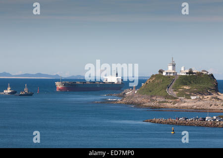 Navire à charbon passant devant le phare de Nobbys Head à l'approche de son quai à Newcastle, Nouvelle-Galles du Sud, Australie Banque D'Images