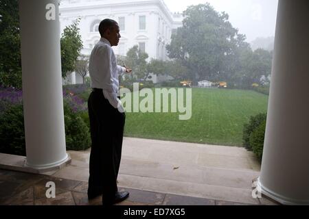 Le président américain Barack Obama tend la main pour toucher la pluie à partir de la colonnade de la Roseraie de la Maison Blanche le 15 octobre 2014 à Washington, DC. Banque D'Images