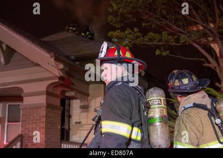 Les équipes de pompiers de Milwaukee Leutenant regarder sur le toit d'une maison avec un feu électrique Banque D'Images