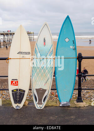 Planches de surf de mer liée contre la rambarde, à l'extérieur de la boutique par la jetée à Dharamsala, Cleveland, UK Banque D'Images
