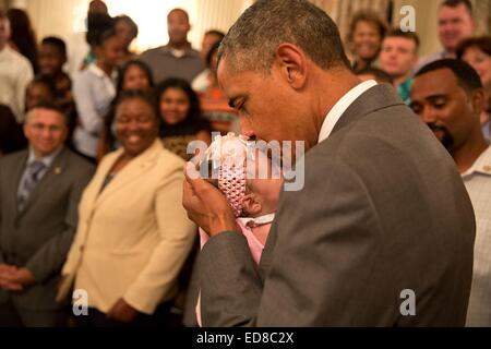 Le président américain Barack Obama embrasse une fille de bébé qu'il saluait les soldats blessés et leurs familles durant leur tournée dans l'East Room de la Maison Blanche le 23 juin 2014 à Washington, DC. Banque D'Images