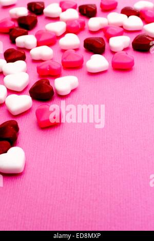 Valentines Day candy formant une frontière sur un fond texturé rose Banque D'Images