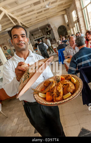 Un serveur affiche un tajine de fruits de mer typique servie au restaurant Haroun. La Marsa, Houmt Souk, Djerba Tunisie. Banque D'Images