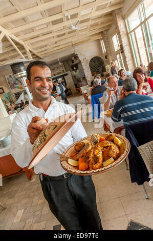 Un serveur affiche un tajine de fruits de mer typique servie au restaurant Haroun. La Marsa, Houmt Souk, Djerba Tunisie. Banque D'Images