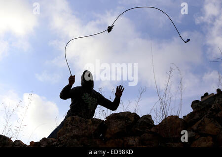 Ramallah, Cisjordanie. 2 Jan, 2015. Un manifestant palestinien utilise une fronde de jeter des pierres sur les forces de sécurité israéliennes au cours d'affrontements près de la prison d'Ofer, près de la ville de Ramallah, en Cisjordanie. © Shadi Hatem/APA/Images/fil ZUMA Alamy Live News Banque D'Images