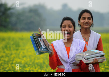 Village du Bangladesh les filles vont à l'école dans le champ avec les manuels scolaires à l'extérieur rassemblement de Dhaka. Banque D'Images