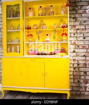 Jaune vif coloré welsh dresser avec ses étagères remplies de bocaux en verre décoratif des ingrédients de cuisine et décorées wit Banque D'Images