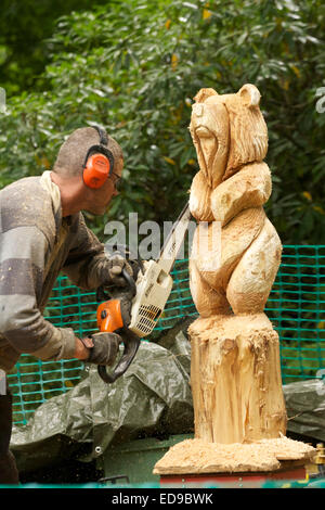 Sculpteur sur bois sculpture d'un supporter sur un tronc d'arbre à l'aide d'une scie Banque D'Images