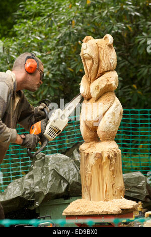 Sculpteur sur bois sculpture d'un supporter sur un tronc d'arbre à l'aide d'une scie Banque D'Images