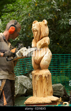 Sculpteur sur bois sculpture d'un supporter sur un tronc d'arbre à l'aide d'une scie Banque D'Images