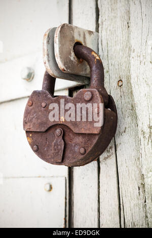 Grand vieux cadenas rouillé hanging on white porte rural Banque D'Images