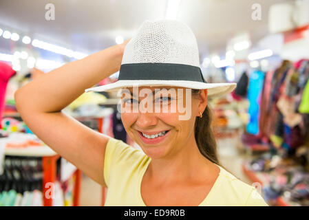 Jolie fille essaie on a white hat dans le magasin Banque D'Images