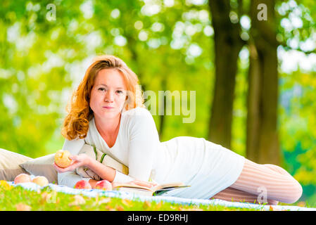 Femme avec une pomme posée sur le week-end dans le parc Banque D'Images