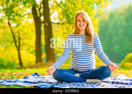 Happy pregnant woman détente sur la pelouse dans le parc Banque D'Images