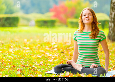 Barefoot fille rousse la pratique du yoga dans le parc en automne Banque D'Images