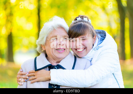 Petite-fille et grand-mère embrassant in autumn park Banque D'Images