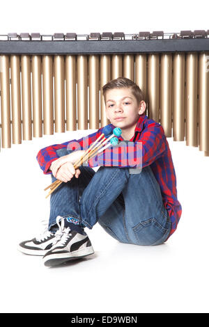 Teenage boy se situe sous marimba dans studio against white background Banque D'Images