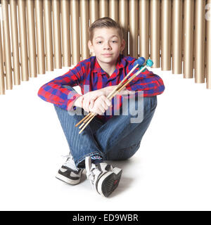 Teenage boy se situe sous marimba dans studio against white background Banque D'Images