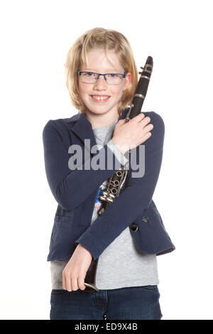 Jeune fille blonde en bleu détient la clarinette dans studio against white background Banque D'Images