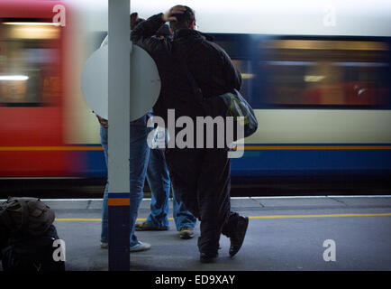 L'homme en attente d'un train à la gare centrale de Southampton avec un train en direction de passé illustré avec le flou. Banque D'Images