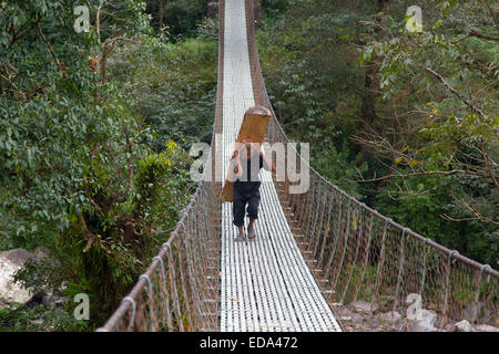 Villager portant de lourdes se connecter sur suspension bridge à Birethanti Modi Khola Valley Népal Banque D'Images