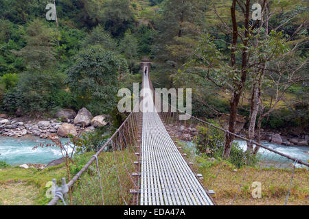 Villager portant de lourdes se connecter sur suspension bridge à Birethanti Modi Khola Valley Népal Banque D'Images