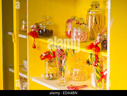 Assortiment de bonbons sucrés sur pots en verre transparent à étagères jaune Banque D'Images