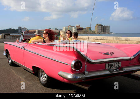 Les touristes voyageant dans une voiture décapotable vintage classique le long du Malecon de La Havane, Cuba Banque D'Images