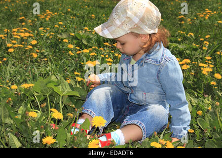 Petite fille aux pissenlits. Banque D'Images