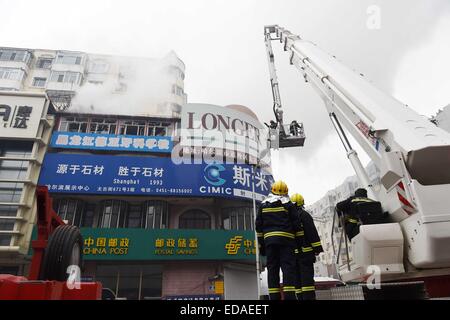 (150104) -- HARBIN, le 4 janvier 2015 (Xinhua) -- Les pompiers essayez de faire tomber les panneaux publicitaires au cours d'une mission d'extinction d'incendie sur un holocauste à l'entrepôt dans Beifangnanxun marché céramique Daowai District, Harbin, capitale de la province du nord-est de la Chine, le 4 janvier 2014. L'entrepôt blaze à Harbin City qui a tué 5 pompiers n'a toujours pas été complètement éteint, les pompiers a dit dimanche. À partir de 10:40 heures dimanche, un bâtiment résidentiel à côté de l'entrepôt a été fumaient encore. Les sauveteurs ont dit que l'origine de l'incendie a été difficile à déterminer en raison de l'immeuble' Banque D'Images