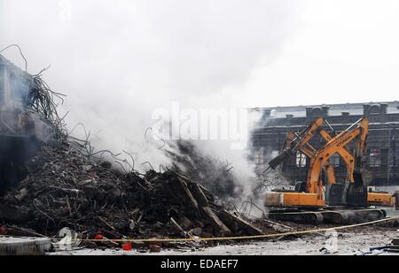 (150104) -- HARBIN, le 4 janvier 2015 (Xinhua) -- la machinerie lourde, nettoyer les débris d'un entrepôt brûlé à l'Beifangnanxun marché céramique en District Daowai, Harbin, capitale de la province du nord-est de la Chine, le 4 janvier 2014. L'entrepôt blaze à Harbin City qui a tué 5 pompiers n'a toujours pas été complètement éteint, les pompiers a dit dimanche. À partir de 10:40 heures dimanche, un bâtiment résidentiel à côté de l'entrepôt a été fumaient encore. Les sauveteurs ont dit que l'origine de l'incendie a été difficile à déterminer en raison de la structure complexe du bâtiment, et le bâtiment est à r Banque D'Images