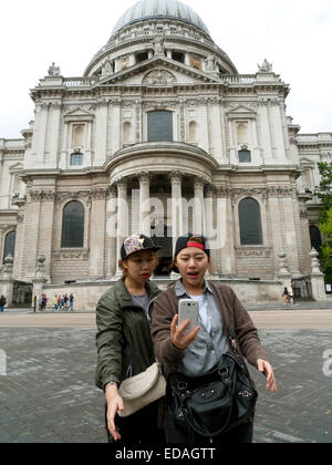 Deux jeunes filles asiatiques chinoises touristes prenant un selfie avec un téléphone mobile à l'extérieur de St. Paul's Cathedral Central à Londres Angleterre Royaume-Uni KATHY DEWITT Banque D'Images