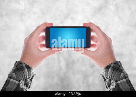 Mains tenant votre smartphone en position verticale avec écran bleu blanc comme Copy Space Banque D'Images