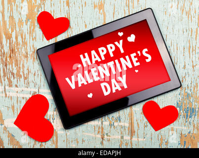 Happy Valentine's Day Message sur l'ordinateur tablette numérique sur old grunge texture bois. Banque D'Images