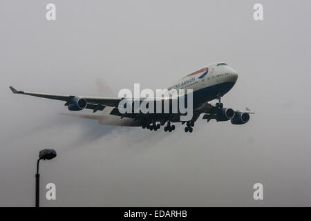 3 janvier 2015, l'aéroport de Heathrow, Londres. Les nuages bas et la pluie fournissent des conditions idéales pour observer service et 'vortex' débourrage comme humidité se condense sur les ailes d'avion à l'atterrissage. Avec la piste visible uniquement à la dernière minute, plusieurs avions ont dû effectuer une 'go-round', abandonnant leurs premières tentatives à la terre. Sur la photo : la vapeur d'eau à partir de la diffusion en continu d'ailes d'un British Airways Boeing 747 jumbo jet se dégage de l'nuages bas instants avant le toucher des roues sur la piste d'Heathrow 27L. Banque D'Images