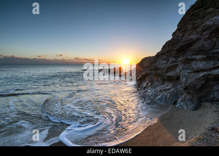 Coucher de soleil sur des roches à Hemmick Beach sur la côte sud des Cornouailles Banque D'Images