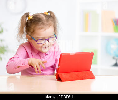 Kid with tablet PC dans des verres avec intérêt l'apprentissage Banque D'Images