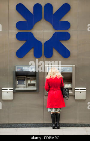 Une femme à l'aide d'un distributeur de billets de la RBS. Banque D'Images