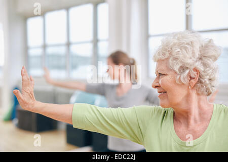 Piscine shot of senior woman doing stretching à l'exercice de yoga. Les femmes pratiquant le yoga à la salle de sport. Banque D'Images