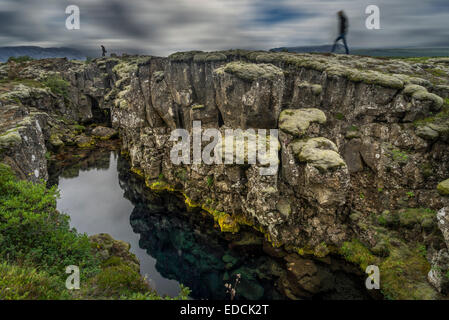 Personnes debout par Flosagja fissure, le Parc National de Thingvellir, Islande Banque D'Images